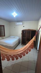 a hammock in a room with a bed and a cabinet at Casas de Praia do Coqueiro com AR e varandas in Luis Correia
