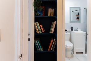a book shelf filled with books next to a toilet at Spacious 2-Bedroom Apartment NYC-10 mins away in Union City