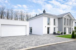 a white house with a large garage at Nivas Collection - Neubau Luxus Apartment in Montabaur