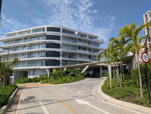 a large white building with palm trees in front of it at Apartamento en Manzanillo con salida directa a la playa in Cartagena de Indias