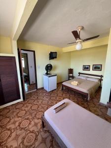 a bedroom with two beds and a ceiling fan at Pousada do Nilo in Itapemirim