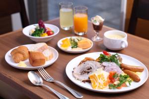 a table with plates of breakfast foods and drinks at Mitsui Garden Hotel Okayama in Okayama +2 photos