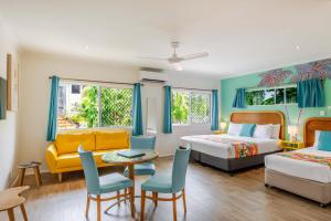 a hotel room with two beds and a table and chairs at Port Douglas Motel in Port Douglas +45 photos