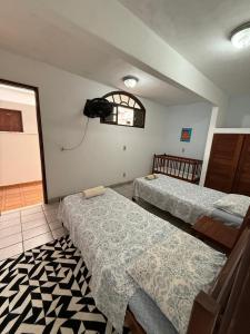 a room with three beds and a television on the wall at Pousada do Nilo in Itapemirim
