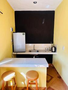 a small kitchen with a sink and two stools at Posada el Sol in El Cuyo