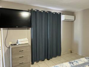 a bedroom with a curtain and a tv and a dresser at Mirador de San Miguel in San Miguel de Allende