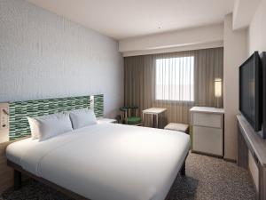 a hotel room with a bed and a television at Mitsui Garden Hotel Okayama in Okayama