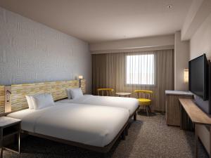 a hotel room with a large bed and a television at Mitsui Garden Hotel Okayama in Okayama