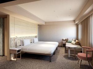 a bedroom with a large bed and a couch at Mitsui Garden Hotel Okayama in Okayama