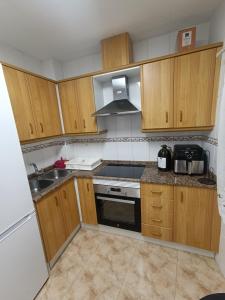 a kitchen with wooden cabinets and a stove top oven at Casa el Pato Lolo in Bolbaite