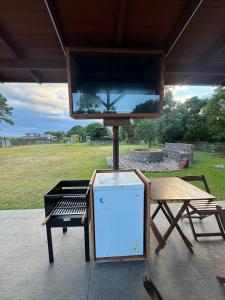 a bbq grill with a screen next to a picnic table at Apartamento de frente para lagoa -Ap 101 in Laguna