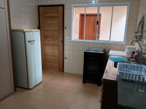 a kitchen with a refrigerator and a stove and a window at Casa Tapajos in Ubatuba