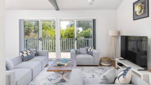 a living room with a couch and a tv at Port View on the Peninsula in Lemon Tree Passage