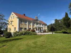 a large yellow house with a large yard at Ribbingshof Herrgård - Flygeln in Norra Vi