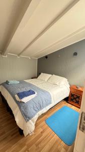 a bedroom with a large bed with a blue rug at Hospedaje Avenida in Puerto Montt