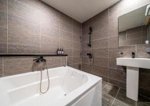 a bathroom with a white tub and a sink at Hotel Petit Gimpo in Gimpo
