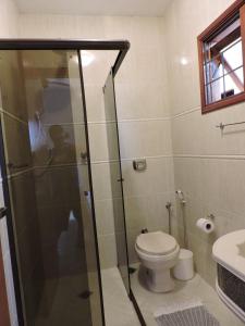 a bathroom with a toilet and a glass shower at Casa Do Sol in São Thomé das Letras