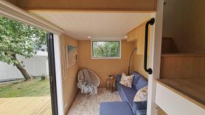 a tiny house with a blue couch and a window at The Tiny Diamond in Diamond Harbour