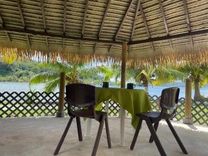 a table and two chairs under a straw roof at Havaii Spot Huahine in HUH