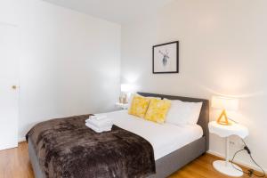 a white bedroom with a bed with yellow pillows at Comfortable Loft Living in Footscray in Melbourne