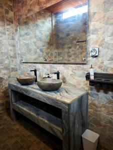 a bathroom with a stone sink and a mirror at Goroadventures and Dive Resort in Gorontalo
