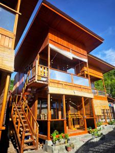 a large wooden building with a staircase in front of it at Goroadventures and Dive Resort in Gorontalo