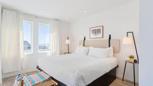 a bedroom with a bed with white sheets and a window at 2 Studios at Cayucan Bungalows by AvantStay in Cayucos