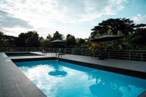 a swimming pool with blue water and an umbrella at Ma Villa Khao Yai in Mu Si