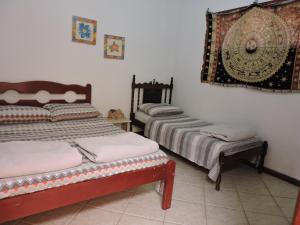 a room with two beds and a chair in it at Casa Do Sol in São Thomé das Letras