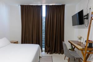 a hotel room with a bed and a desk and a window at Hotel Punto Oriente Tonala in Tonalá