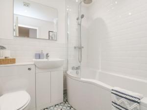 a white bathroom with a tub and a sink and a toilet at The Nest in Bridlington
