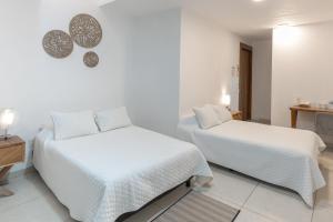 two beds in a room with white walls at Hotel Punto Oriente Tonala in Tonalá