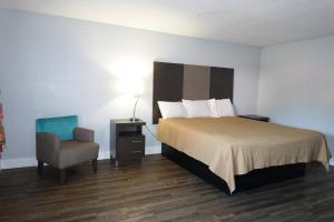 a hotel room with a bed and a chair at Cascades Motel - Chattanooga in Chattanooga
