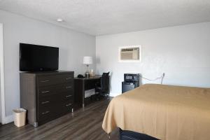 a bedroom with a bed and a desk with a television at Cascades Motel - Chattanooga in Chattanooga