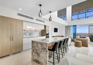a kitchen with a large island with bar stools at Bokarina Beachfront Penthouse - Oceanfront Luxury with Exclusive Rooftop Pool & Steam Room in Bokarina