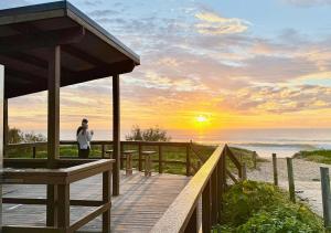 a person standing on a wooden walkway to the beach at Bokarina Beachfront Penthouse - Oceanfront Luxury with Exclusive Rooftop Pool & Steam Room in Bokarina