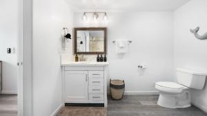 a white bathroom with a toilet and a mirror at Strand Way B by AvantStay in Oceano +21 photos