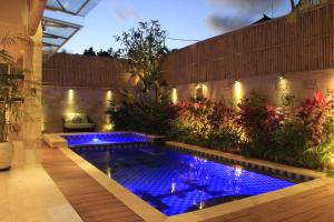 a swimming pool in a garden with blue lights at Villa Margaux in Seminyak