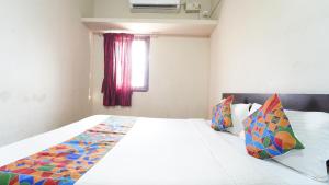 a bedroom with a large white bed with colorful pillows at Peelamedu PSG Tech Near Rooms in Coimbatore +1 photo
