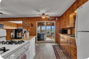a kitchen with white appliances and wooden walls at The Cozy Cub in Cross Lake