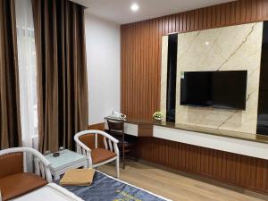 a hotel room with a desk and a television on a wall at Ruby 25 Hotel in Hà Ðông