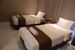 a hotel room with two beds with white and brown sheets at Wakayapa Syariah Residence in Dahung