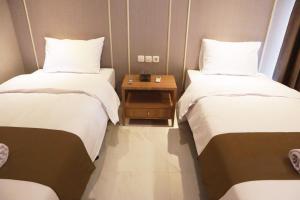 two beds in a room with a table between them at Wakayapa Syariah Residence in Dahung