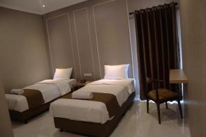 a hotel room with two beds and a chair at Wakayapa Syariah Residence in Dahung