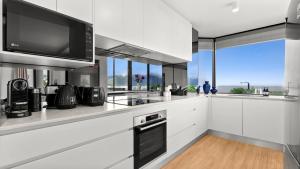 a kitchen with white cabinets and a flat screen tv at The Condo at Northshore Tower in Cairns North