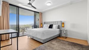 a white bedroom with a bed and a balcony at The Condo at Northshore Tower in Cairns North