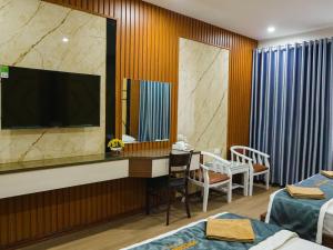a hotel room with a tv and a desk with a mirror at Ruby 25 Hotel in Hà Ðông