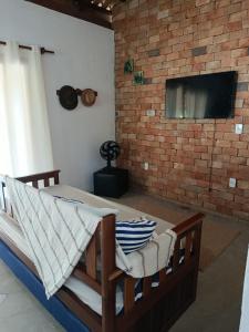 a bedroom with a bed and a tv on a brick wall at Casa de pedra in Prado