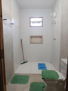 a bathroom with a shower and a toilet and green mats at Casa de pedra in Prado +12 photos