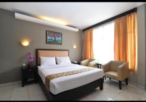 a hotel room with a bed and a chair at Hotel GRANDSARASWATI in Stasiun Poncol